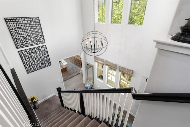 staircase featuring an inviting chandelier, baseboards, and carpet flooring