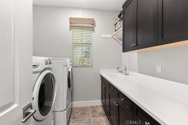 laundry area featuring light tile patterned floors, a sink, baseboards, washer and dryer, and cabinet space