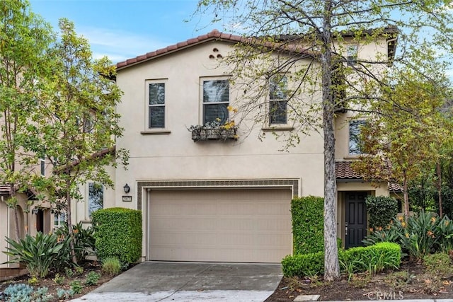 mediterranean / spanish home with concrete driveway, an attached garage, a tile roof, and stucco siding