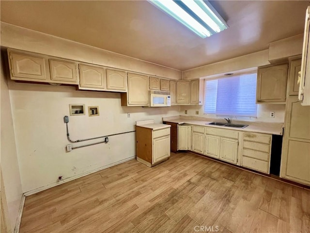 kitchen featuring light countertops, a sink, light wood-style flooring, and white microwave