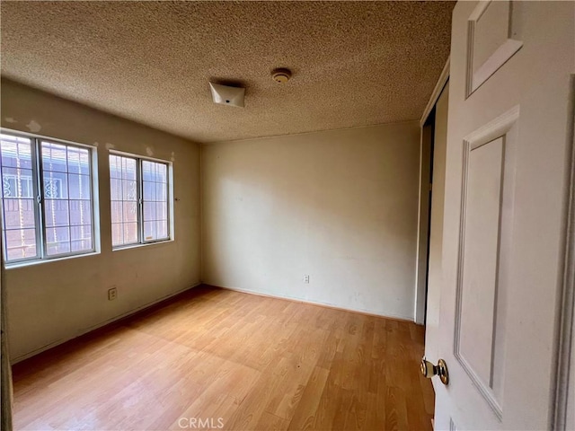 spare room featuring light wood-style flooring and a textured ceiling