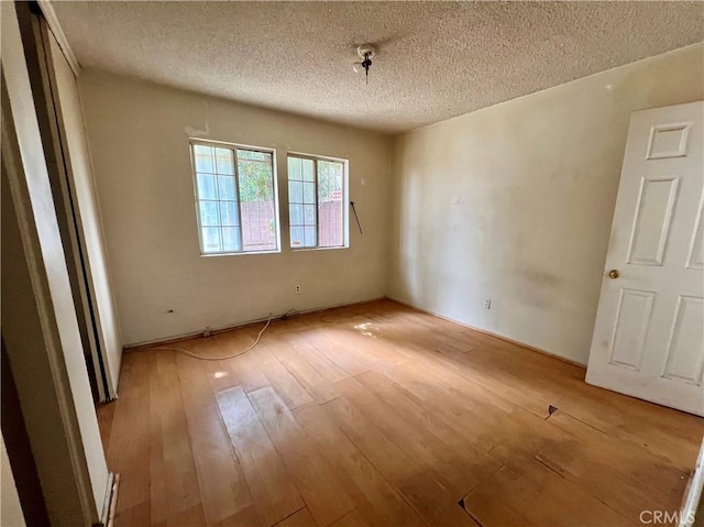 unfurnished room featuring wood-type flooring and a textured ceiling