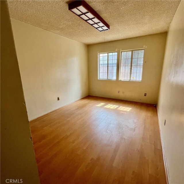 unfurnished room with a textured ceiling and light wood finished floors