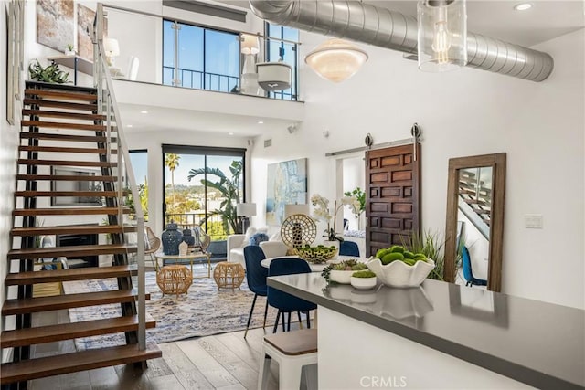 interior space featuring recessed lighting, stairway, a high ceiling, a barn door, and hardwood / wood-style floors