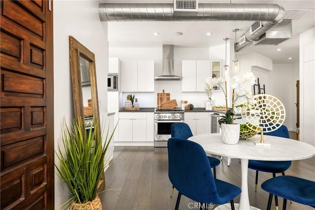 kitchen featuring wall chimney range hood, modern cabinets, visible vents, and high end stove