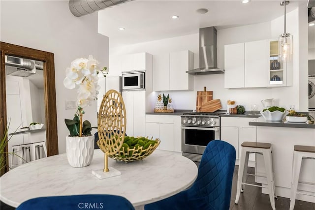 kitchen with white microwave, high end stainless steel range oven, white cabinets, modern cabinets, and wall chimney exhaust hood