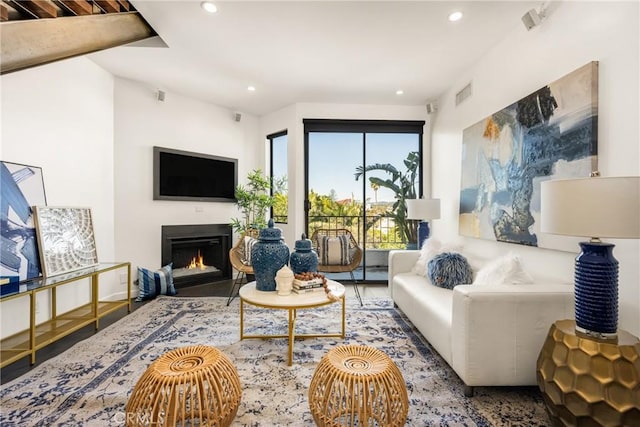 living room with recessed lighting, visible vents, a lit fireplace, and wood finished floors