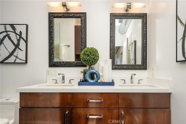 bathroom with double vanity, toilet, and a sink