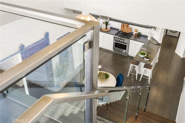 interior space with dark countertops, high end stove, white cabinets, and dark wood-type flooring