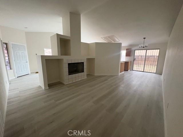 unfurnished living room featuring light wood-type flooring, a fireplace, and an inviting chandelier