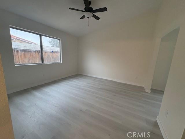 spare room with ceiling fan, vaulted ceiling, and light wood-type flooring