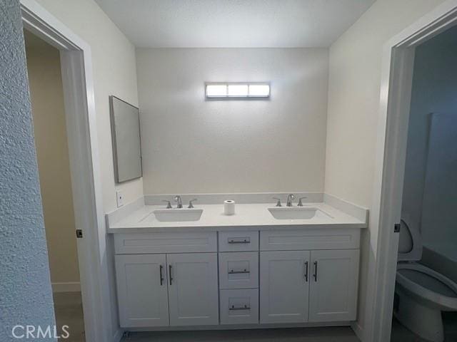 full bath with double vanity, toilet, and a sink