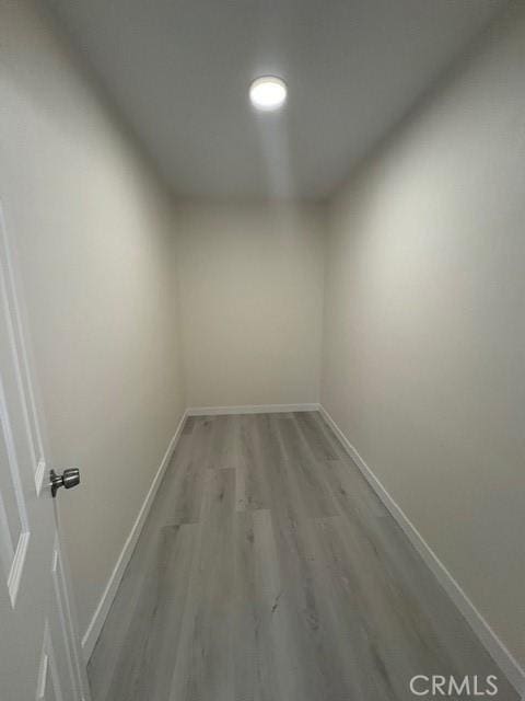 hallway featuring light wood-style flooring and baseboards