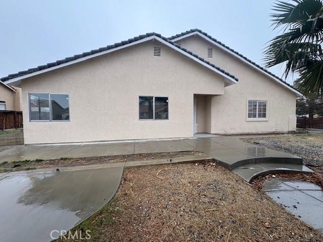 rear view of property with a patio area, fence, and stucco siding