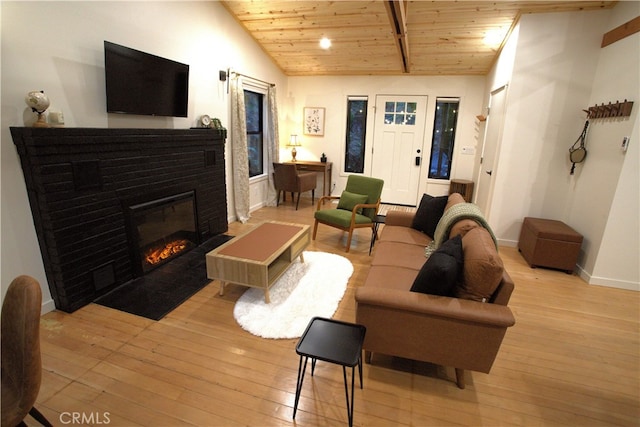 living room featuring vaulted ceiling with beams, wooden ceiling, a fireplace with flush hearth, baseboards, and light wood finished floors