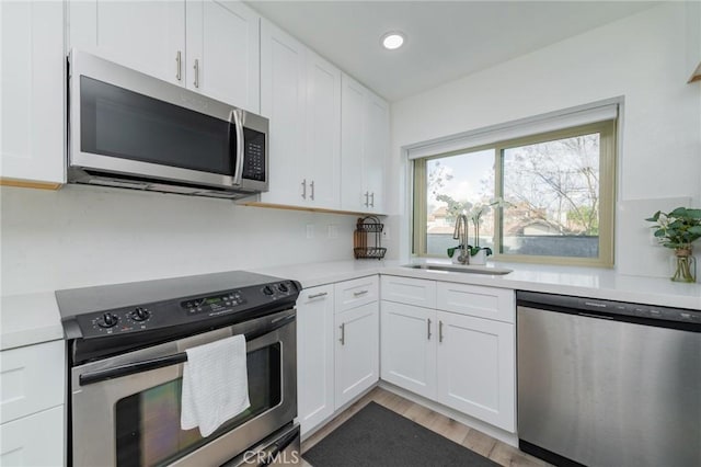 kitchen featuring light countertops, appliances with stainless steel finishes, a sink, and white cabinets