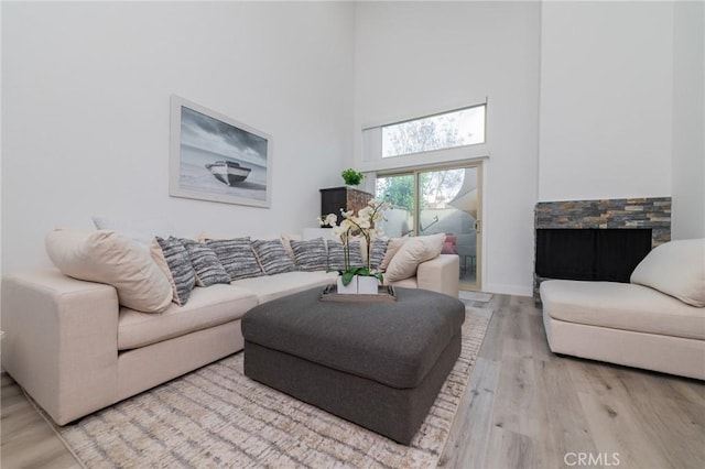 living area featuring a high ceiling, baseboards, and wood finished floors