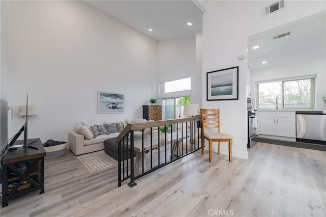 living area with light wood-style floors, a wealth of natural light, and visible vents