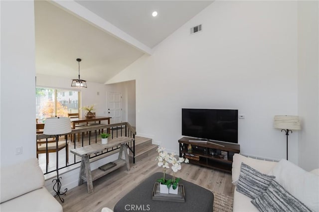 living area with high vaulted ceiling, light wood-style flooring, visible vents, stairway, and beamed ceiling