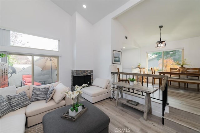 living room featuring high vaulted ceiling, light wood-type flooring, a healthy amount of sunlight, and recessed lighting