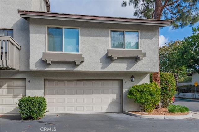 view of front of home featuring driveway, an attached garage, and stucco siding