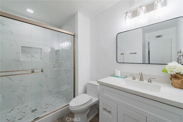 bathroom featuring toilet, a marble finish shower, visible vents, and vanity