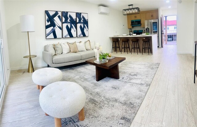 living area featuring baseboards, light wood-style flooring, and a wall mounted AC