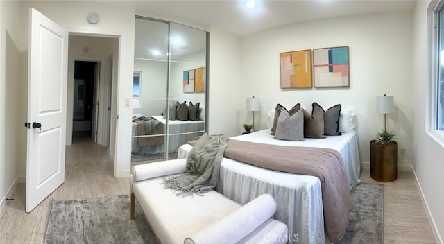 bedroom with a closet, light wood finished floors, and baseboards