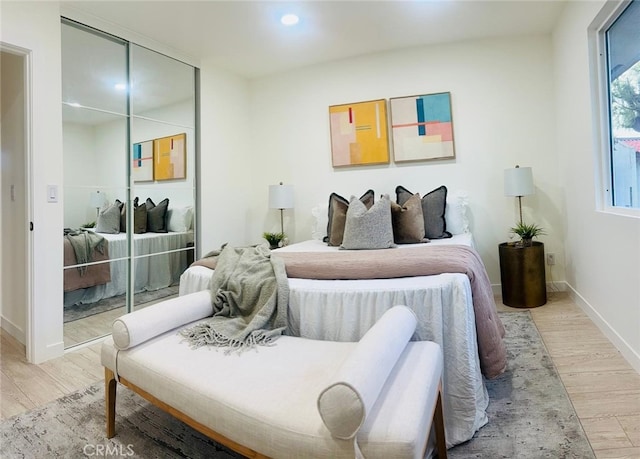 bedroom featuring light wood-type flooring, baseboards, and a closet