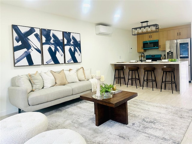 living area featuring a wall mounted air conditioner, light wood-type flooring, and baseboards