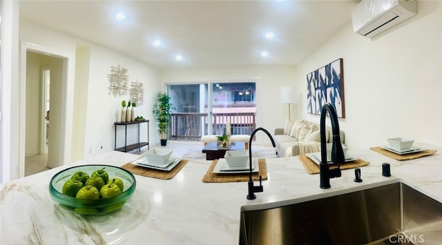 interior space featuring open floor plan, light stone countertops, a wall mounted air conditioner, and a sink