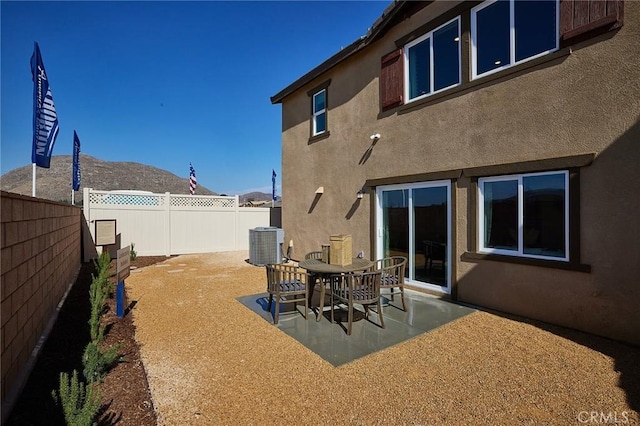 back of house with stucco siding, central AC unit, a patio area, a mountain view, and a fenced backyard