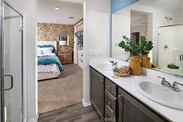 ensuite bathroom with wallpapered walls, a sink, connected bathroom, and a shower stall