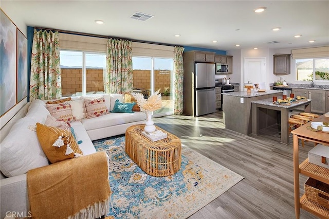 living room with recessed lighting, visible vents, and light wood-style flooring