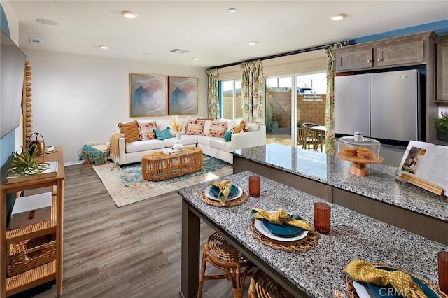 living room with recessed lighting, visible vents, baseboards, and wood finished floors