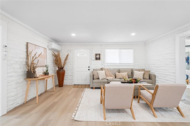 living room with crown molding, brick wall, light wood-type flooring, and a wall mounted air conditioner