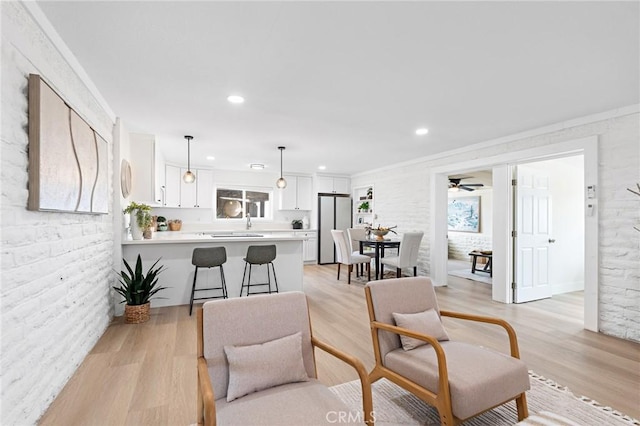 living area with brick wall, recessed lighting, a ceiling fan, and light wood-style floors