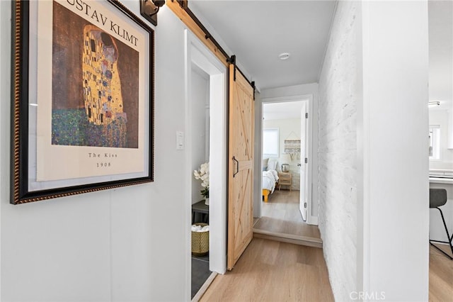 hall featuring light wood finished floors and a barn door