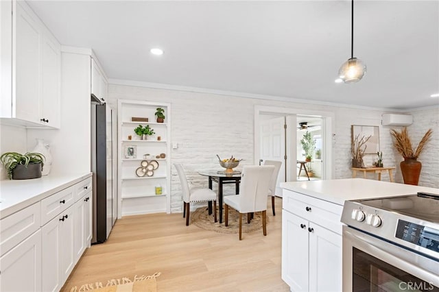 kitchen featuring a wall unit AC, white cabinetry, appliances with stainless steel finishes, light wood-type flooring, and crown molding