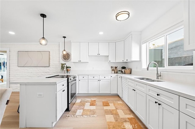 kitchen featuring a peninsula, a sink, white cabinetry, light countertops, and stainless steel electric range