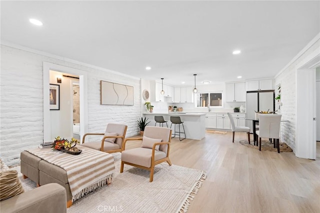 living area with recessed lighting, light wood-style flooring, and crown molding