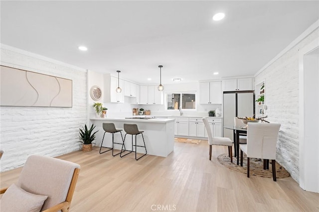 kitchen featuring a peninsula, white cabinetry, light countertops, light wood-type flooring, and freestanding refrigerator