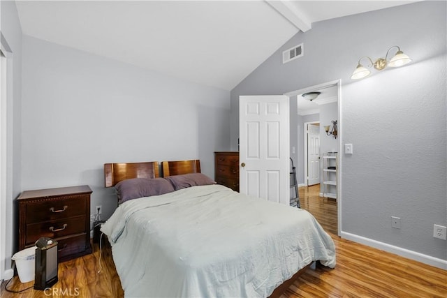 bedroom featuring vaulted ceiling with beams, baseboards, visible vents, and wood finished floors