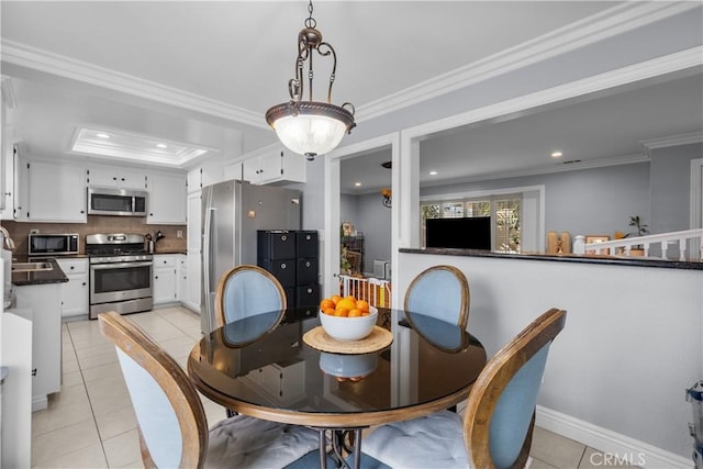 dining space with ornamental molding, a raised ceiling, baseboards, and light tile patterned floors