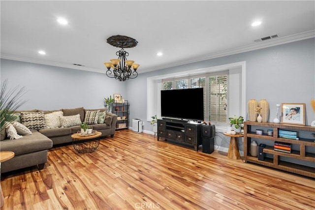 living room featuring ornamental molding, visible vents, a notable chandelier, and wood finished floors