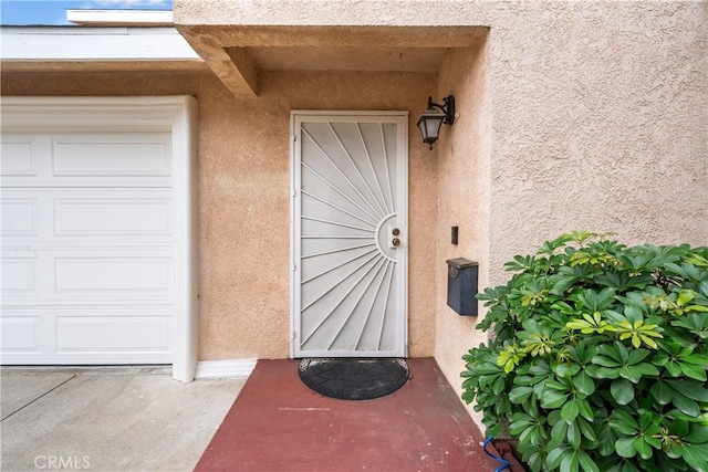 entrance to property featuring a garage and stucco siding