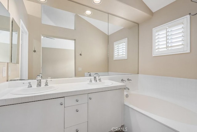 bathroom with vaulted ceiling, double vanity, a sink, and a garden tub