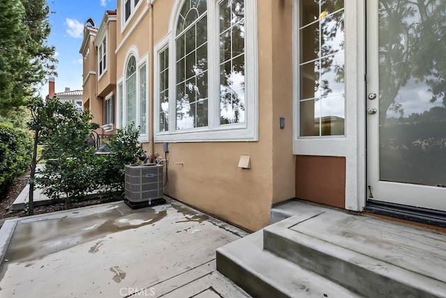 property entrance with stucco siding, a patio, and central AC unit