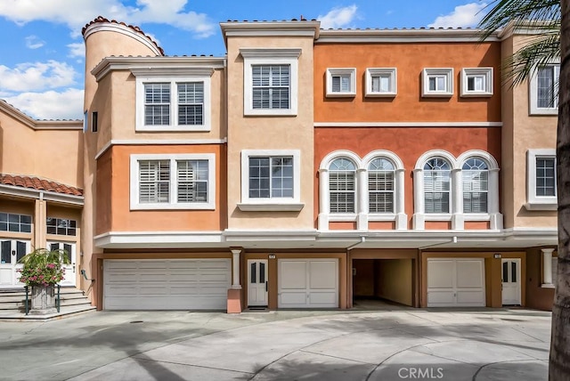 view of front of property with an attached garage, driveway, and stucco siding