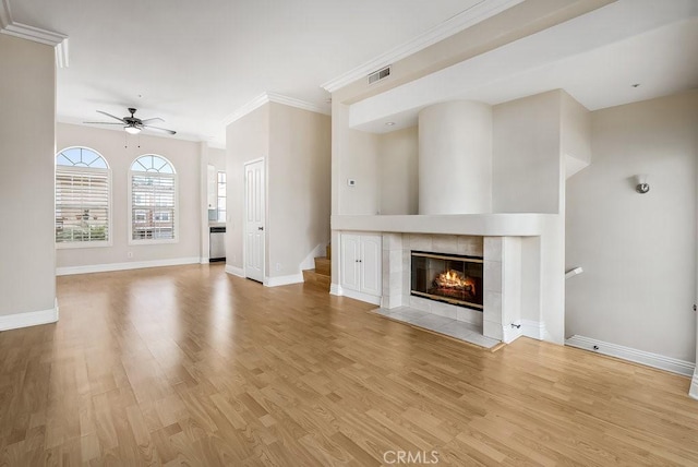 unfurnished living room featuring light wood-style floors, visible vents, crown molding, and a tile fireplace